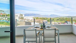 Un balcon avec une table dressée pour deux personnes, offrant une vue sur un paysage montagneux.