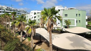 Un bâtiment moderne à plusieurs étages, entouré de palmiers et surplombant un ciel dégagé.