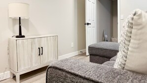 A room with a white cabinet, a lamp, and a grey sofa with a cushion. - RiverStone Retreat C (Newburgh)