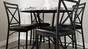 A dining area with a round table, four black chairs, a white vase, and a decorative mirror on the wall. - RiverStone Retreat C (Newburgh)