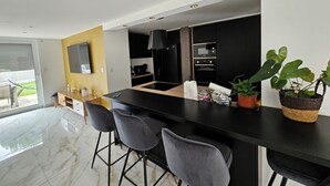 Een moderne keuken met een centraal eiland, barstoelen en een potplant.