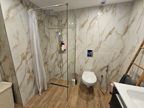 Une salle de bain avec une douche à parois de verre, des toilettes et un lavabo.