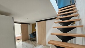 Een modern interieur met een spiltrap, een eethoek en uitzicht op een balkon.