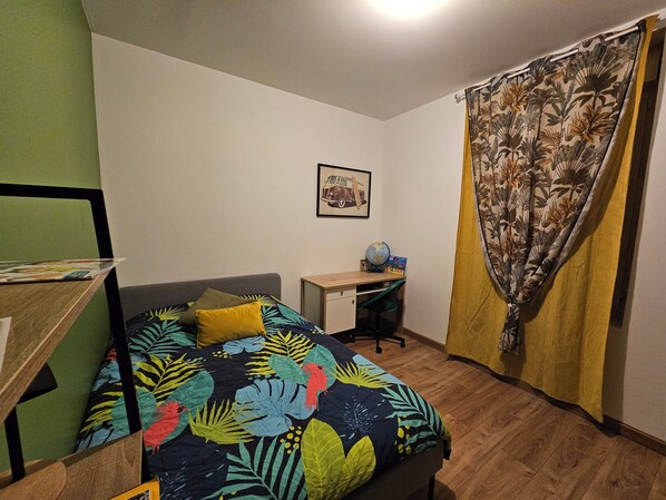 A bedroom with a bed, a desk, and a globe.