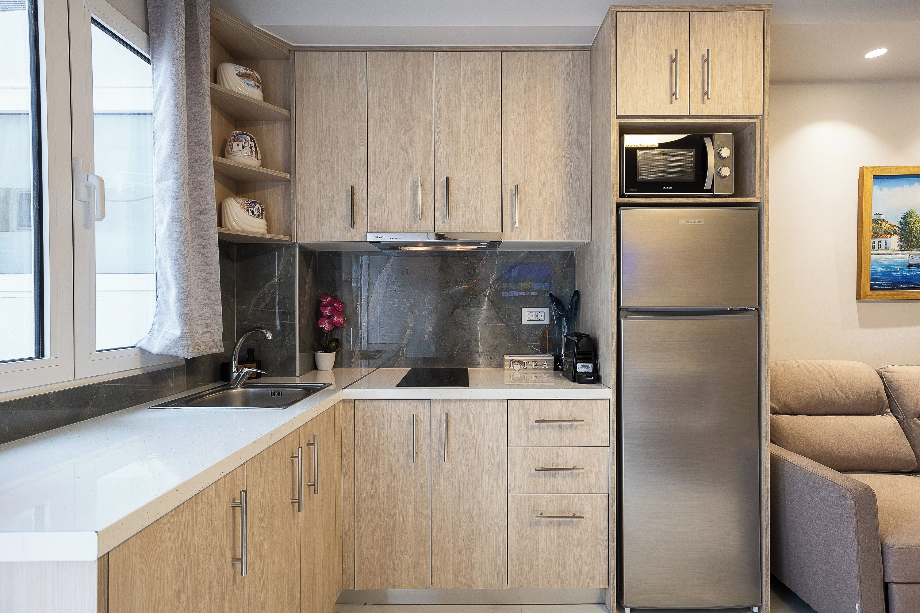 A modern kitchen with wooden cabinets, a stainless steel refrigerator, a microwave, and a sink.