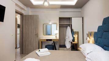 Een moderne hotelkamer met een groot bed, een bureau met spiegel, een kledingkast en een badkamer zichtbaar door een geopende deur.