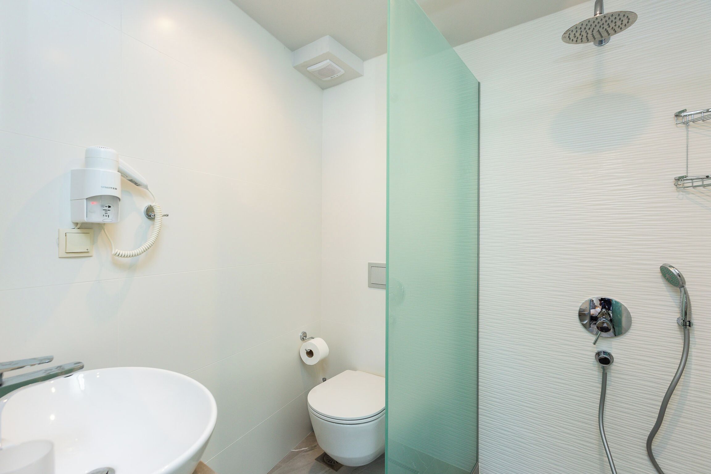 A bathroom with a toilet, sink, and shower.