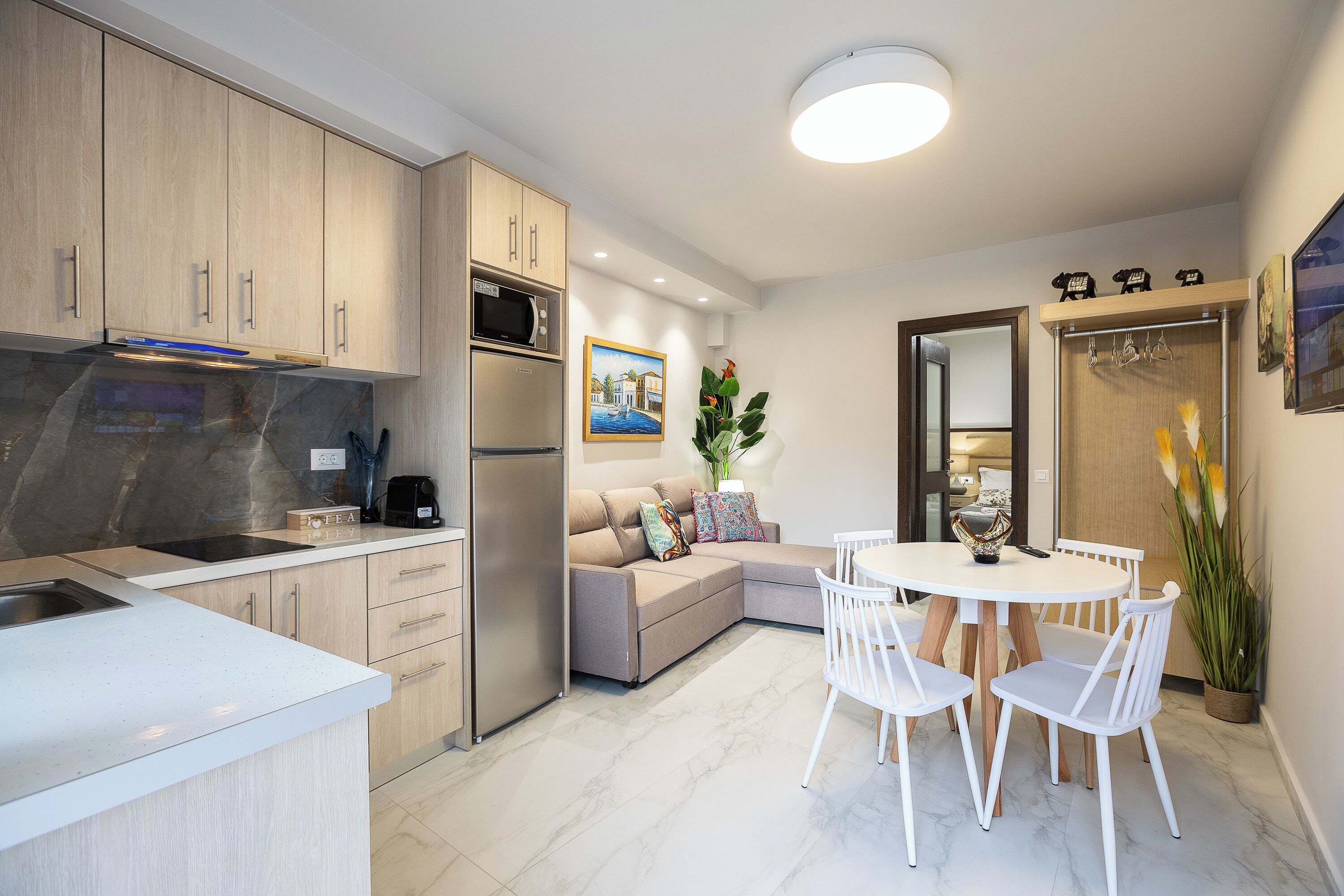A modern kitchen with a built-in microwave, a stainless steel refrigerator, and a white countertop.