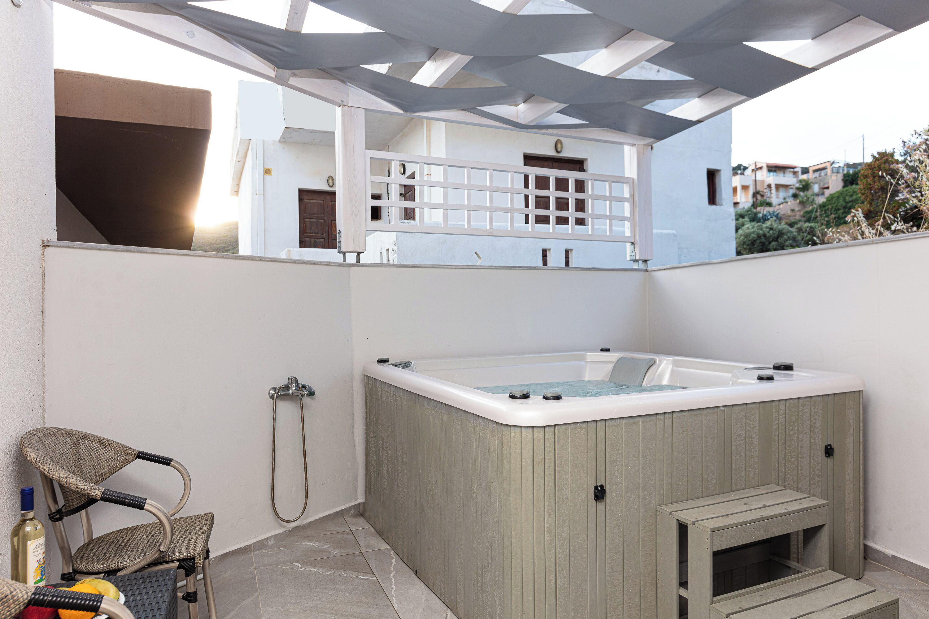 A modern outdoor bathroom with a hot tub, a shower, and a seating area.