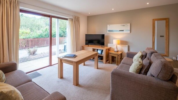 A modern living room with a flat-screen TV, a wooden coffee table, and a sofa. - Pet friendly Croft Cottage (Truro)