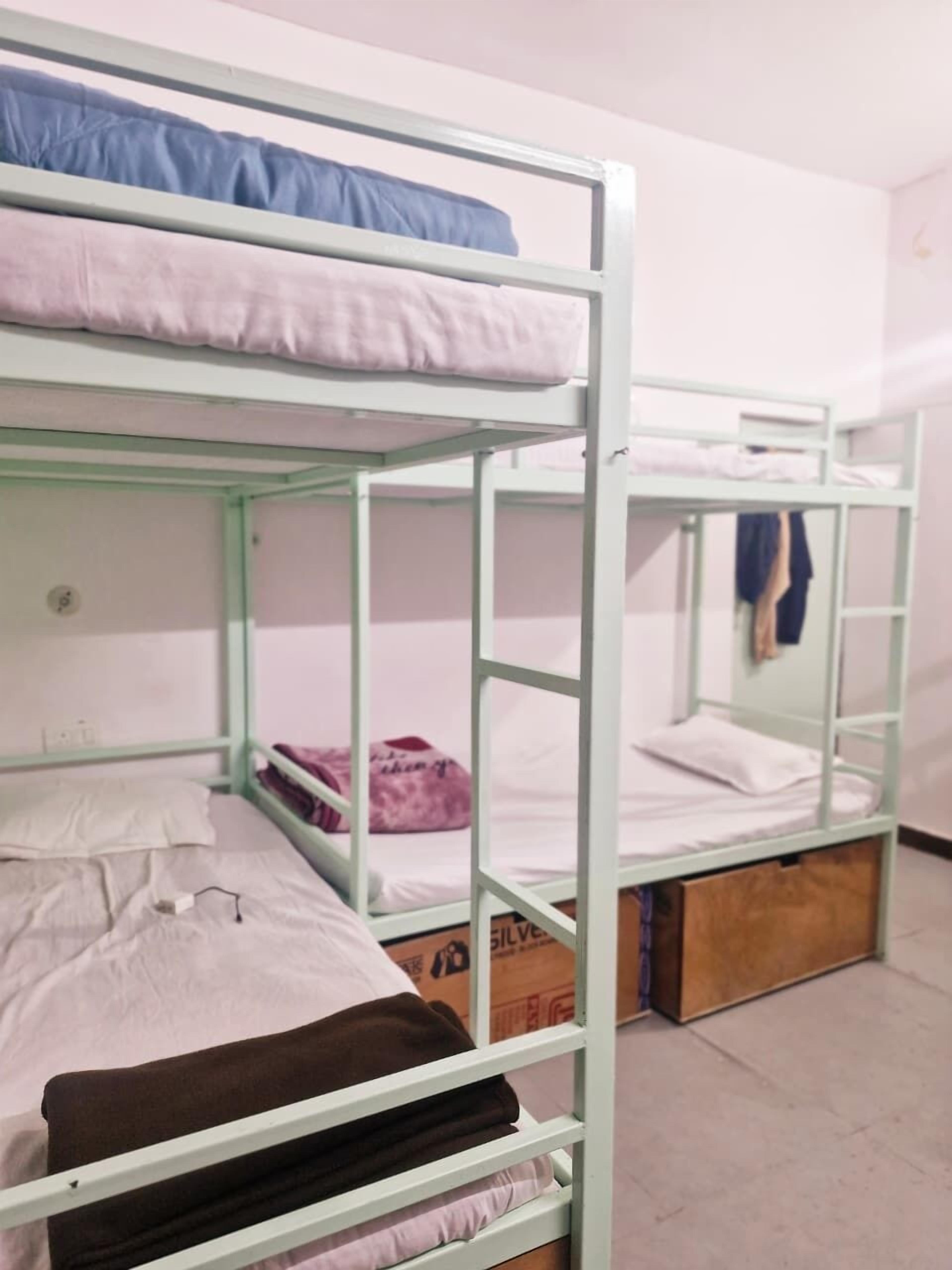 Ein Schlafsaalzimmer mit Etagenbetten, einem Holfach und einem Karton auf dem Boden.