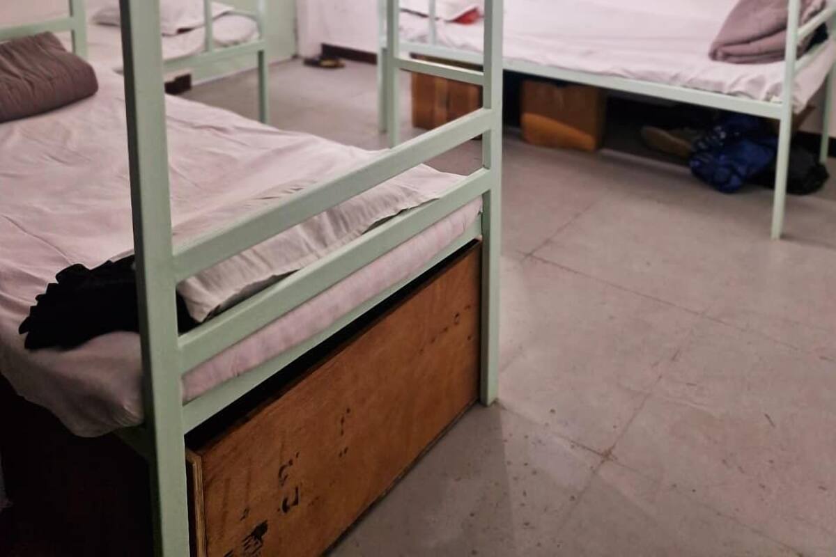 Ein Schlafsaalzimmer mit Etagenbetten, einem Deckenventilator und einem kleinen Tisch mit einem violetten Handtuch.