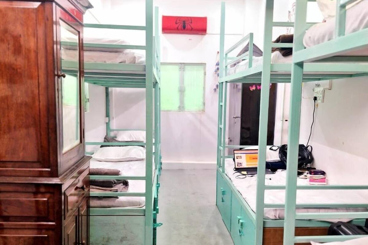 Ein Schlafsaalzimmer mit Etagenbetten, einem Holzschrank und einem Fenster mit grünem Vorhang.