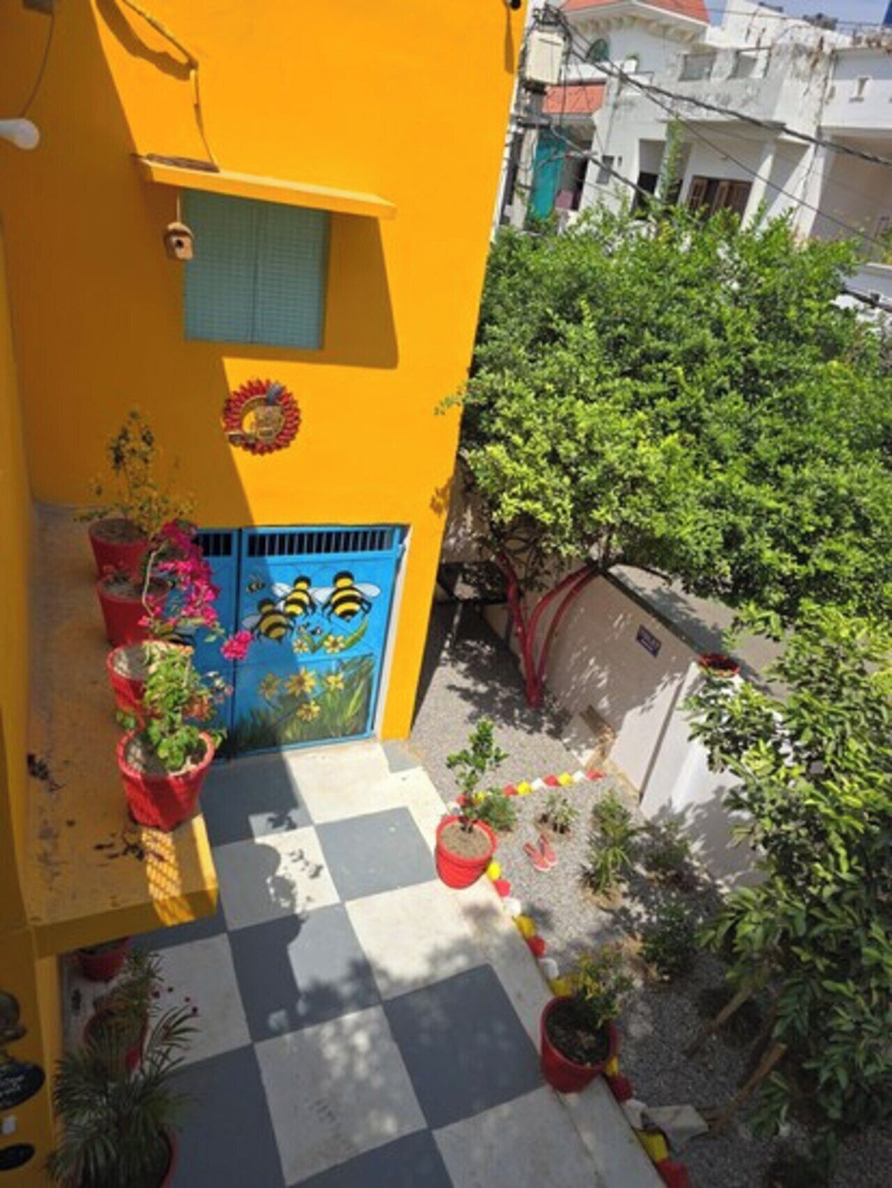 A yellow building with a blue door, potted plants, and a checkered floor.