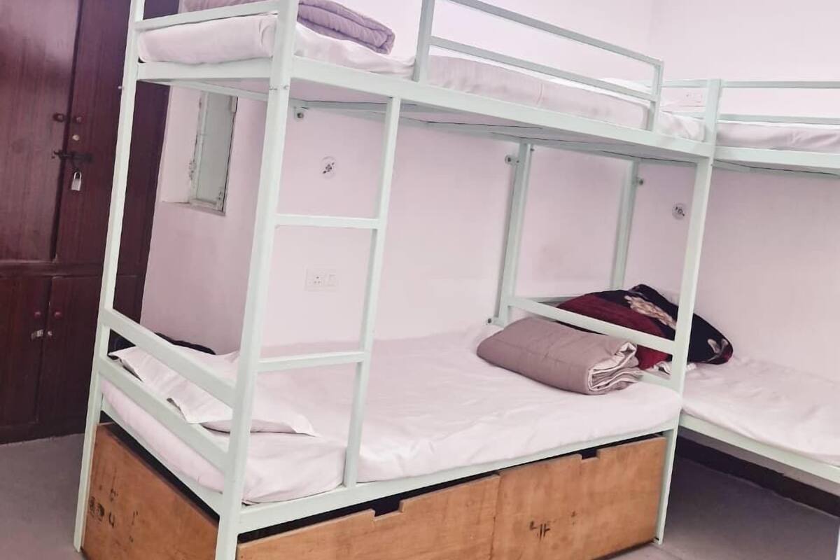 Ein Schlafraum mit Etagenbetten, Holzboden, Deckenventilator und einer Tür.