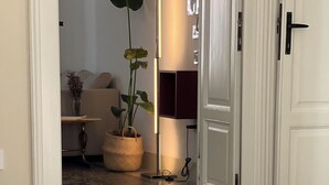 Een hotelkamer met een bed, een potplant en een deur naar een andere kamer.