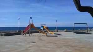 A playground with slides and a swing set by the sea.