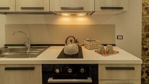 A modern kitchen with a stainless steel sink, a kettle, and a small tea set on the countertop.