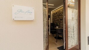 A hotel entrance with a sign reading "Gina Ara casa vecchia" and a contact number.