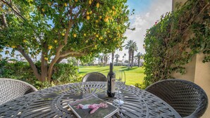 A round outdoor table with wicker chairs, a bottle of wine, and a magazine. - Luxury PGA West  3BR 2BA Condo (La Quinta)