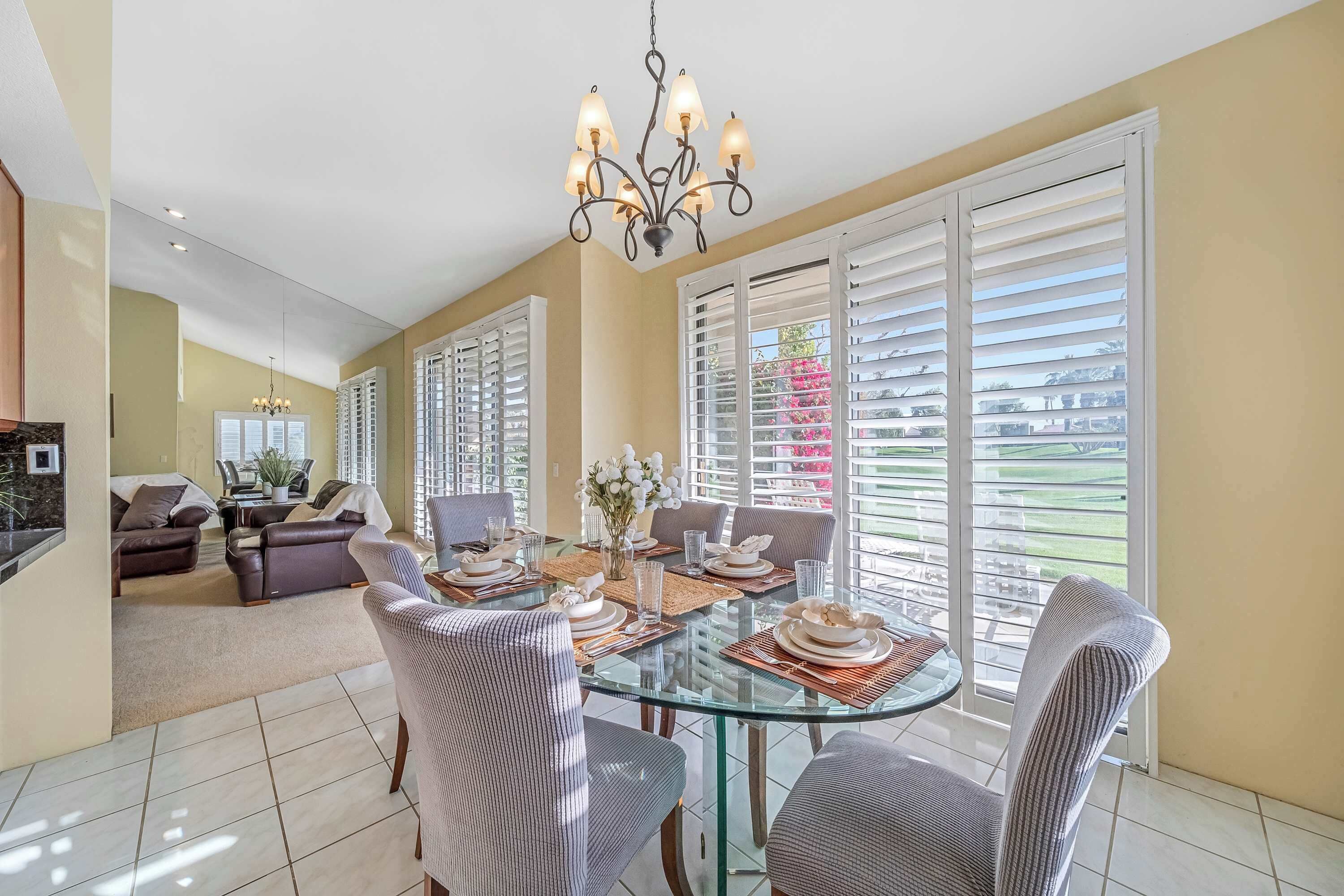 A dining area with a glass table, chairs, and a chandelier.
