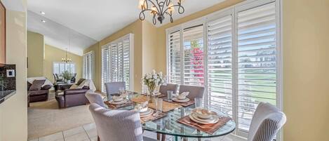 A dining area with a glass table, chairs, and a chandelier.