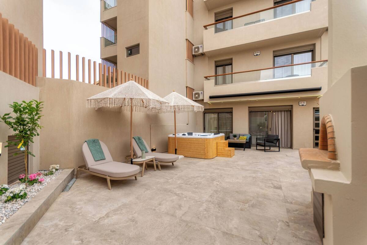 Un espace de détente extérieur moderne, comprenant des fauteuils, un jacuzzi et des parasols.