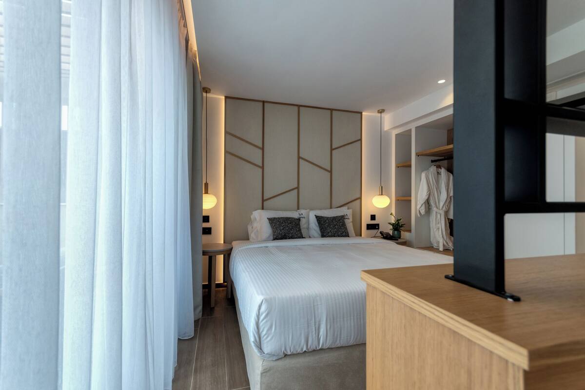 Une chambre d’hôtel moderne équipée d’un lit, de tables de chevet, d’une armoire et d’un téléviseur.