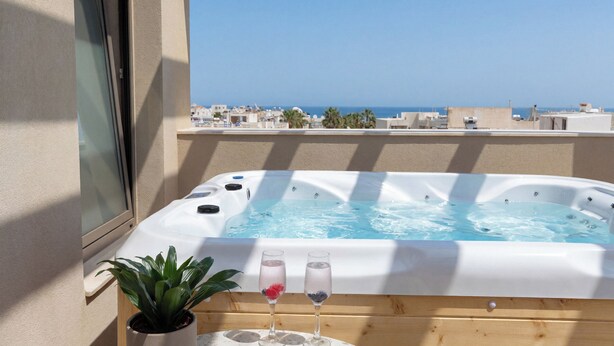 Un bain à remous, deux verres d’eau, une plante en pot et une vue sur la mer.