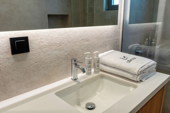 A bathroom with a white sink, a mirror, and a towel rack with folded towels.