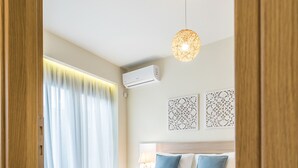 Une chambre avec un lit en bois, un luminaire suspendu et une fenêtre avec des rideaux.