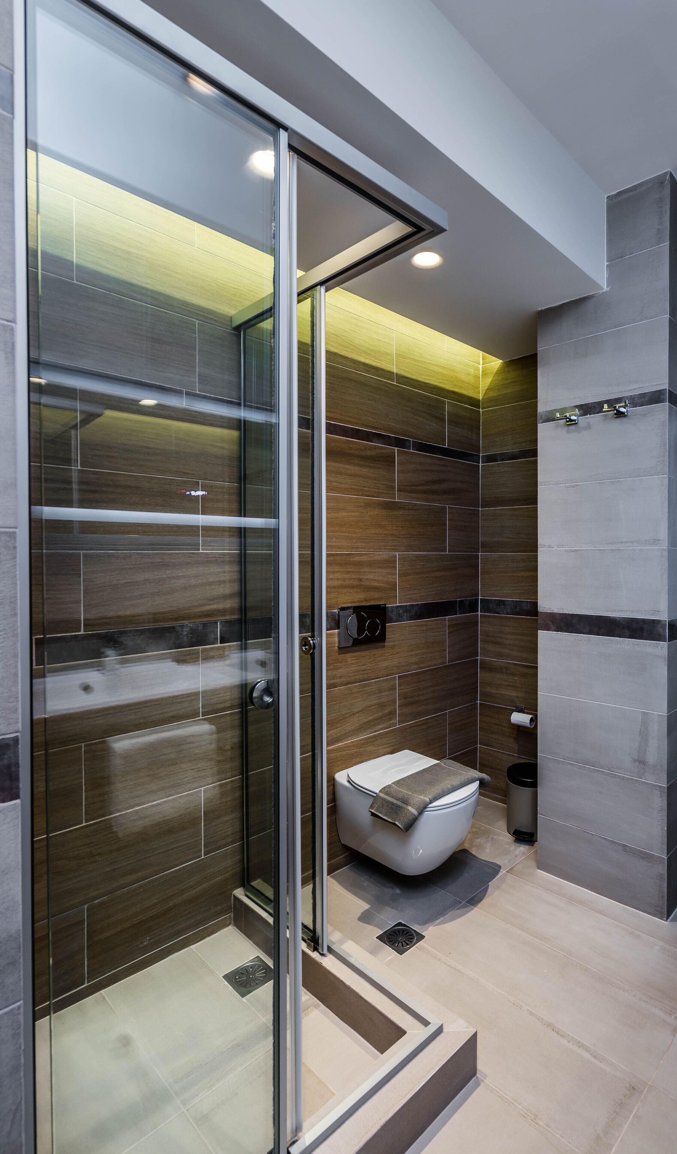 A modern bathroom with a glass shower enclosure, a toilet, and a bidet.