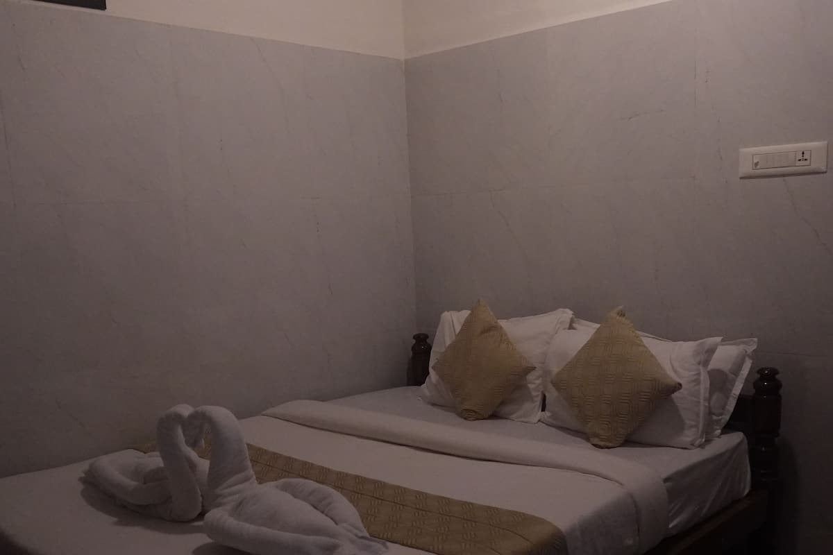 A single bed with two pillows, a blanket, and two towels.