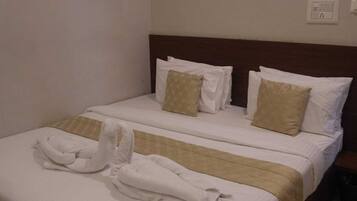 Habitación de hotel con cama doble, dos almohadas, cabecero, mesita de noche y toma de corriente.