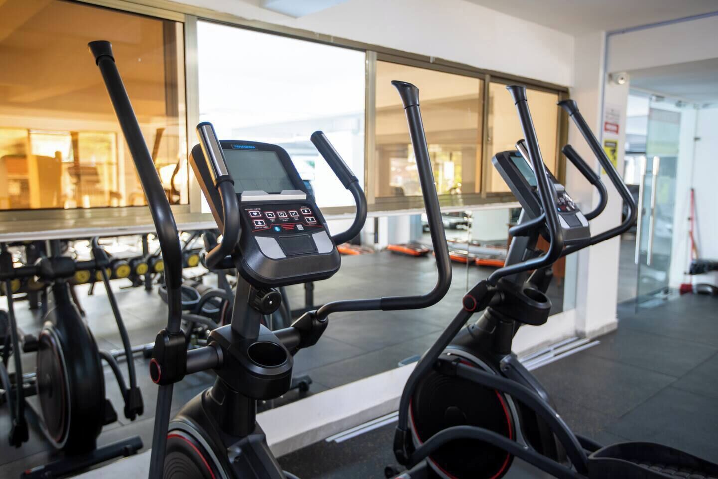 Una hilera de bicicletas estáticas con pantallas digitales, probablemente en un gimnasio o centro de acondicionamiento físico.