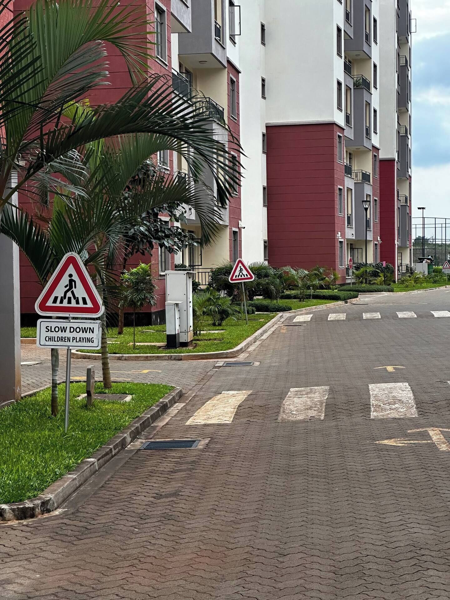 A residential street with a pedestrian crossing sign and a 'SLOW DOWN CHILDREN PLAYING' sign.