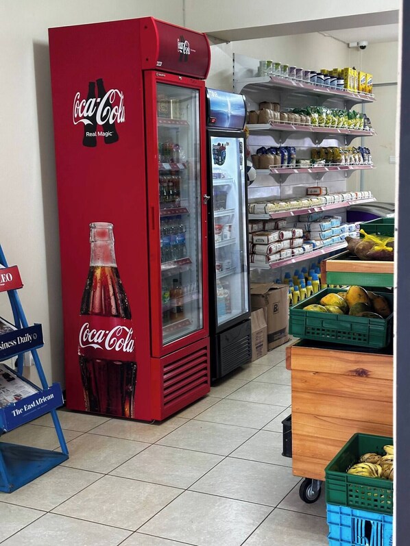 Una máquina expendedora y un refrigerador en una tienda con estantes llenos de diversos productos.