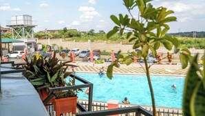 Ein Schwimmbecken mit darin schwimmenden und entspannenden Menschen, umgeben von einem Zaun und Kübelpflanzen.