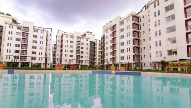 Un complex residencial amb diversos blocs d'apartaments, una piscina i una zona enjardinada ben cuidada.