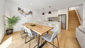 A modern kitchen with white cabinets, a wooden island, and stainless steel appliances. - Fishermen (Torquay)