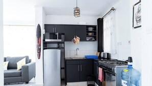 A compact kitchen with modern appliances, a dining area with a sofa, and a large water dispenser.