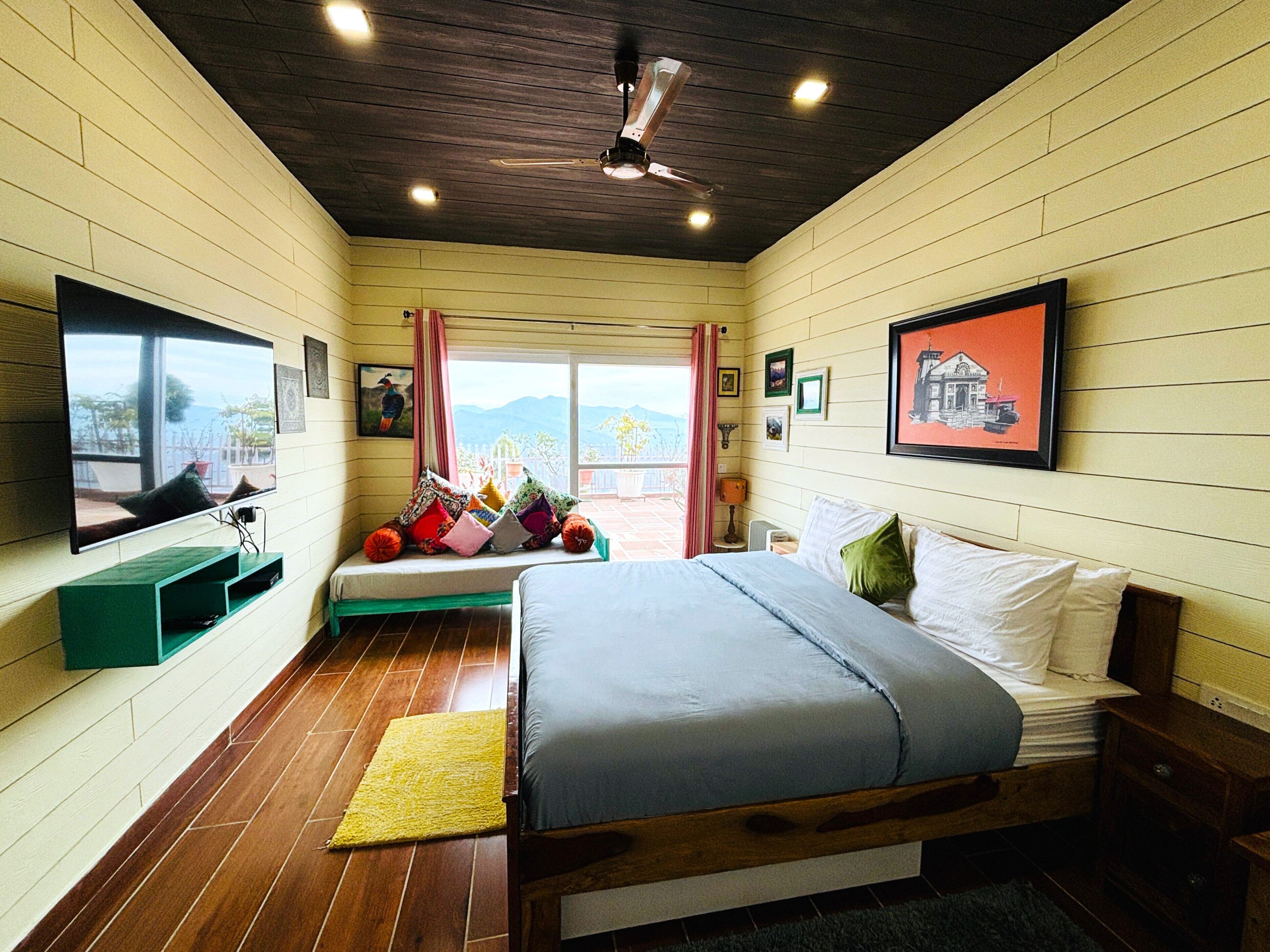 A bedroom with a bed, a window, a ceiling fan, and a view of the outdoors.