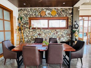 Un coin repas avec un mur en pierre, une table en bois et des chaises en cuir.