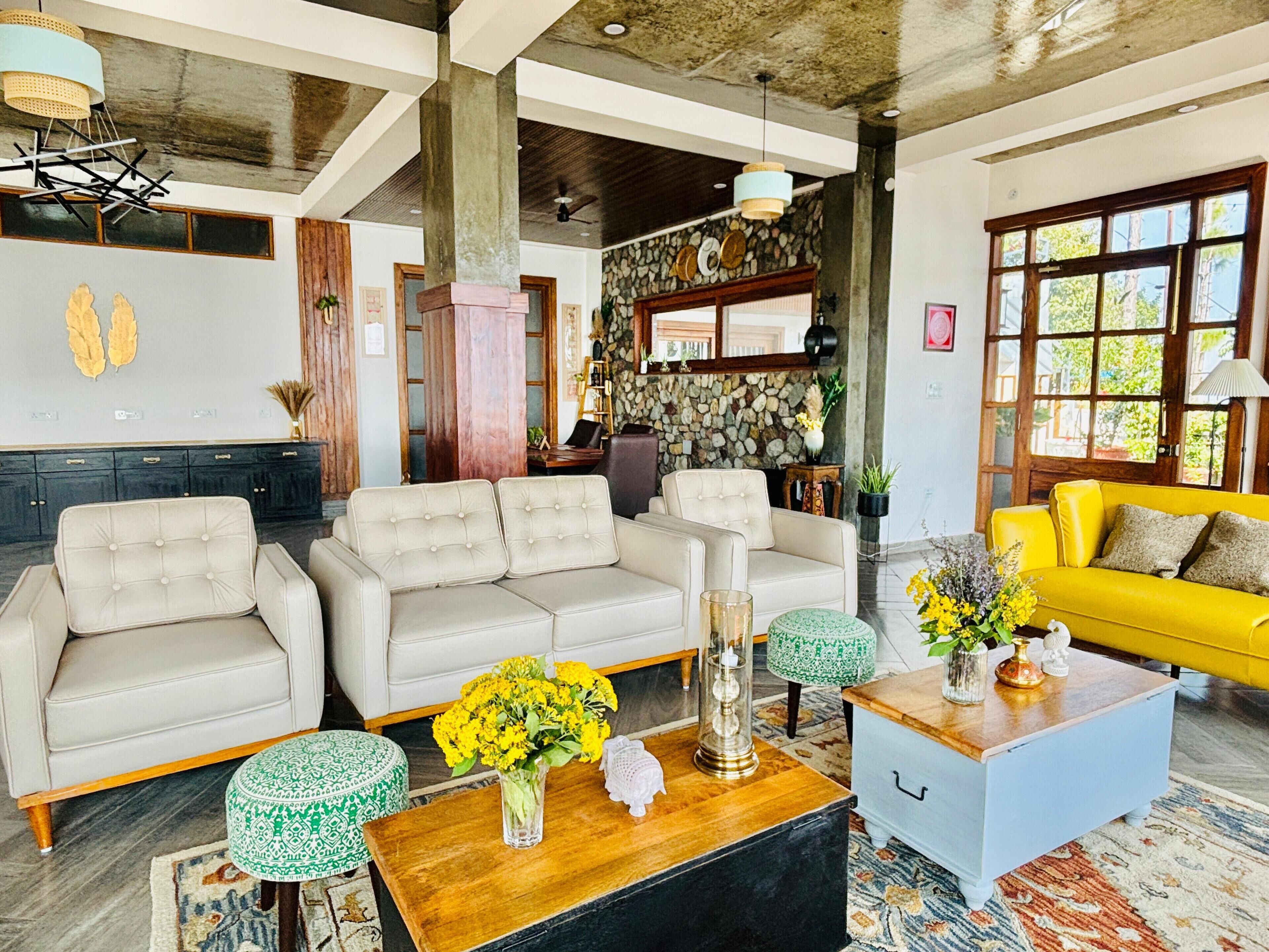 A spacious living area with a large sofa set, a coffee table with flowers, and a bright yellow sofa.