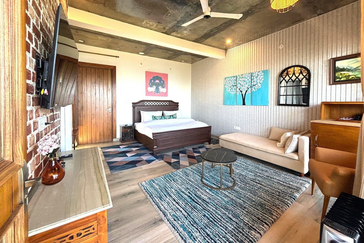 A bedroom with a wooden bed, a sofa, a small table, and a patterned rug.