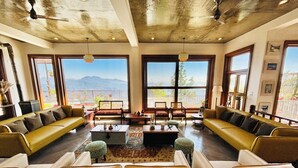 A spacious living room with leather sofas, a coffee table, and large windows offering a mountain view.