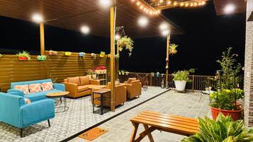 Un patio al aire libre con arreglos de asientos, plantas en macetas y luces colgantes.