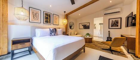 A modern bedroom with a large bed, a ceiling fan, and artwork on the walls.