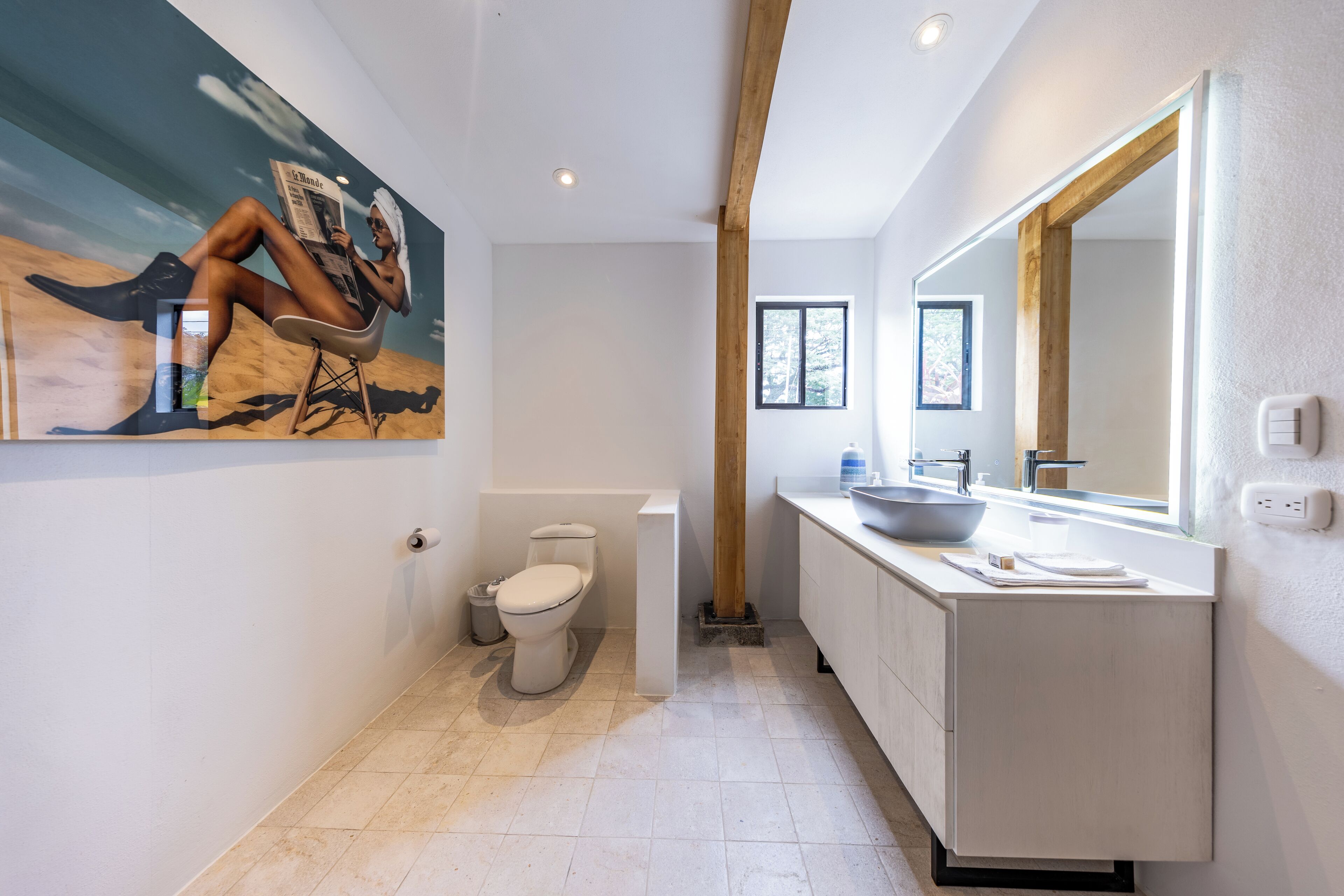 A modern bathroom with a large mirror, a sink, and a toilet.