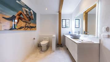 A modern bathroom with a large mirror, a sink, and a toilet.